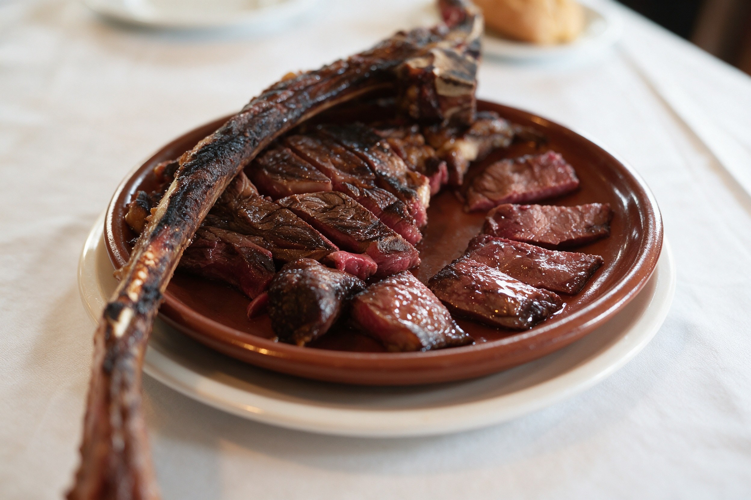 Costillar de ternera a la brasa con corteza dorada y carne tierna en plato de barro